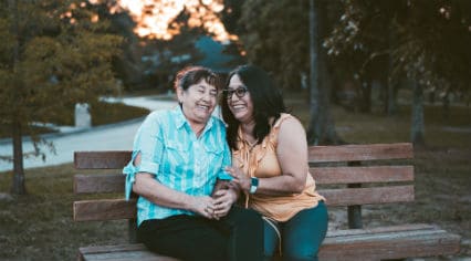 Mother and daughter laughing on a bench