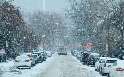 a snowy road with cars parked along both sides