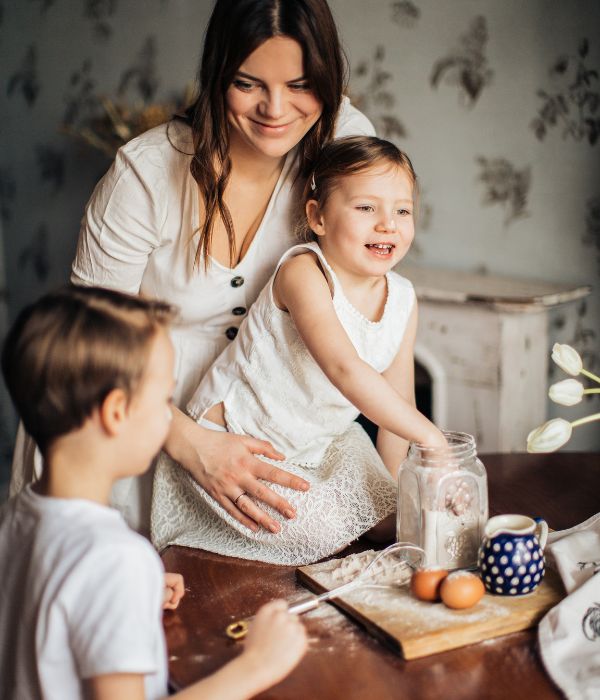 a mom baking at the table with her two young children, smiling knowing they're future is secure after creating a living will